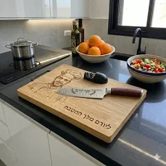 קרש חיתוך מעץ עם חריטה של דיוקן אבא בכובע שף והכיתוב ׳כשרי של אבא׳ על משטח מטבח מודרני